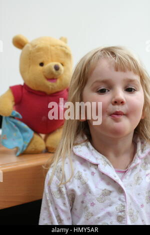 Piccola bambina di tre anni giocando con winnie the pooh divertente l'infanzia, l'innocenza concetto, felice, innocente dolce bambino biondo pjs felice messing Foto Stock