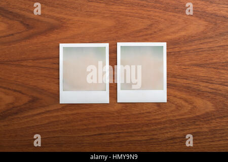 Vuoto stampa istantanea di fotografie su un tavolo di legno. Due oggetti. Foto Stock