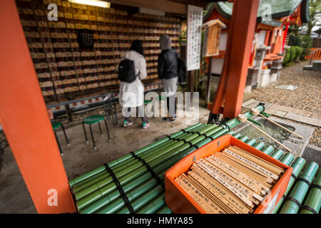 Due turisti in cerca di piccole placche in legno con preghiere e auguri a Fushimi Inari Taisha (sacrario scintoista), Kyoto Foto Stock