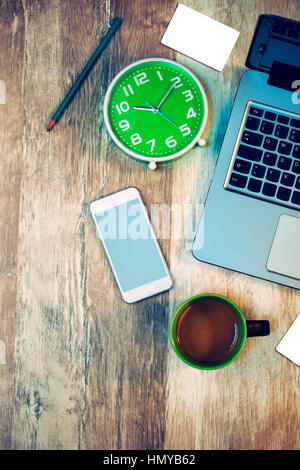 Moderno business office superiore dello spazio di lavoro View con oggetti in legno rustico desk - portatile, telefono cellulare, tazza di caffè, orologio, matita e carte di credito Foto Stock