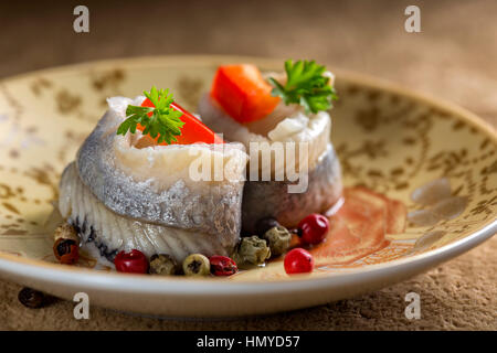 Piastra con marina aringhe marinate pesce con verdure ed erbe su sfondo di velluto Foto Stock