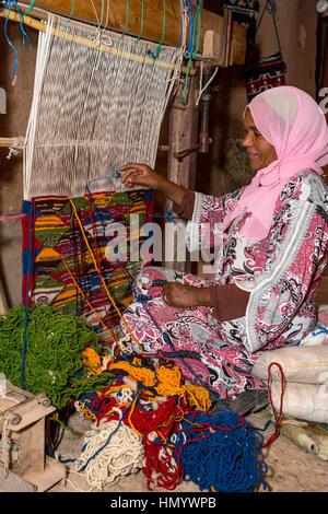 Il Marocco. Berber donna tessitura di un tappeto in casa sua. Ait Benhaddou Ksar, un sito del Patrimonio Mondiale. Foto Stock