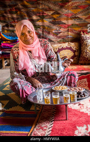 Il Marocco. Donna di etnia Arab-Berber versando il tè per gli ospiti. Ait Benhaddou Ksar, un sito del Patrimonio Mondiale. Foto Stock