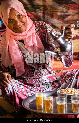 Il Marocco. Donna di etnia Arab-Berber versando il tè per gli ospiti. Ait Benhaddou Ksar, un sito del Patrimonio Mondiale. Foto Stock