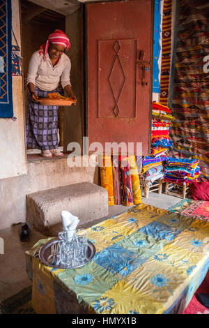 Il Marocco. Donna di etnia African-Berber portando il cous cous alla tabella. Ait Benhaddou Ksar, un sito del Patrimonio Mondiale. Foto Stock