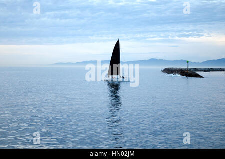 Barca a vela con la vela nera off Redondo Beach Pier Foto Stock