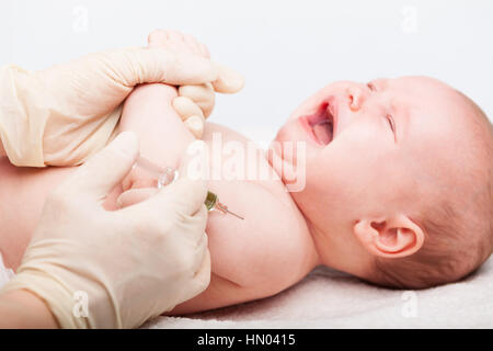 Close-up shot di pediatra dando a tre mesi di baby girl iniezione intramuscolare in braccio Foto Stock
