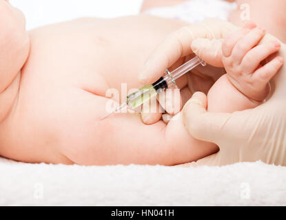 Close-up shot di pediatra dando a tre mesi di baby girl iniezione intramuscolare in braccio Foto Stock