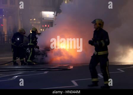 Fire crew mettendo una Toyota Prius che ha preso fuoco in corrispondenza della giunzione di Brompton Road e Brompton Square guardando verso i magazzini Harrods, Londra. Foto Stock