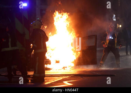 Fire crew mettendo una Toyota Prius che ha preso fuoco in corrispondenza della giunzione di Brompton Road e Brompton Square guardando verso i magazzini Harrods, Londra. Foto Stock