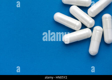 Varie capsule di colore bianco su sfondo blu. Copia dello spazio per il tuo testo. Vista dall'alto, alta risoluzione prodotto. Health care concept Foto Stock