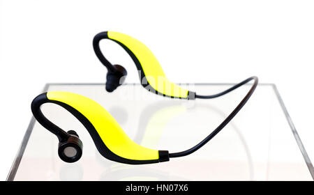 Giallo e nero gli auricolari Bluetooth su una scatola di acrilico su sfondo bianco Foto Stock