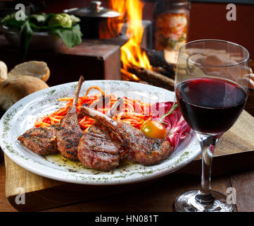 La nervatura di agnello con un bicchiere di vino rosso Foto Stock