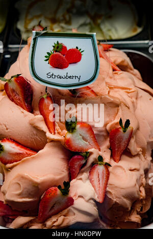 Una grande vasca di fresco gelato alla fragola sul display in un gelato shop Foto Stock