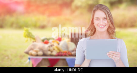 Ritratto di donna felice azienda digitale compressa contro il cibo con ardesia su tavola Foto Stock