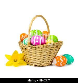Cesto di pasqua con uova colorate e narcisi su sfondo bianco Foto Stock