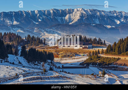 Vista panoramica sulla zona turistica ski resort Cheile Gradistei Fundata e il maestoso snowy Piatra Craiului mountains range, Romania. Foto Stock