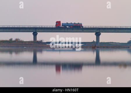 Cargo auto va oltre il ponte nella nebbia oltre il fiume, il trasporto, il trasporto di liquidi Foto Stock