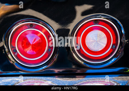 Il colore e la bellezza delle auto d'epoca. Rotondo rosso luci posteriori di un nero auto sportive. Cromato paraurti è coperta con uno spesso strato di polvere Foto Stock
