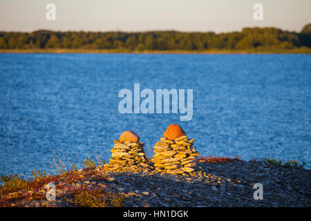 Funny mucchi di ciottoli sul mare sullo sfondo del tramonto Foto Stock