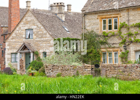 Inglese tradizionale con miele dorato marrone lapidato cottages in un borgo rurale con walled giardini anteriore, su un estate giornata di sole Foto Stock