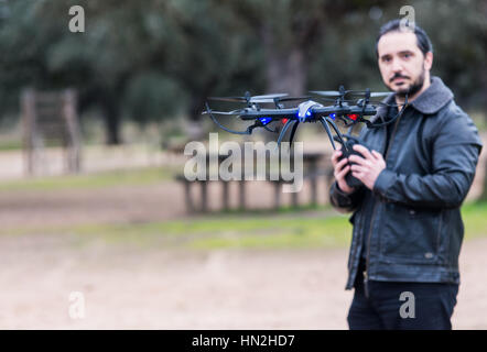 Un uomo il funzionamento del Drone dal telecomando nel Parco Foto Stock