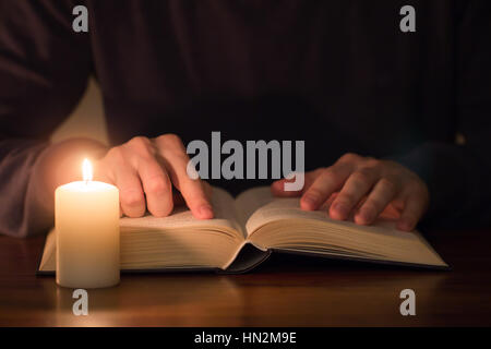 Uomo libro di lettura con la luce di una candela Foto Stock