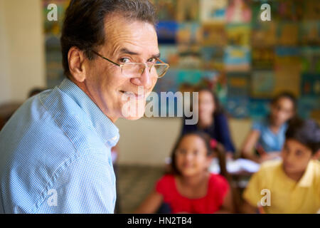 I giovani e l'istruzione. Gruppo di studenti ispanici in classe a scuola durante la lezione. Gentile uomo ispanico lavora come insegnante, ritratto di felice p Foto Stock