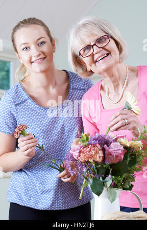 Senior donna con insegnante nella composizione floreale di classe Foto Stock