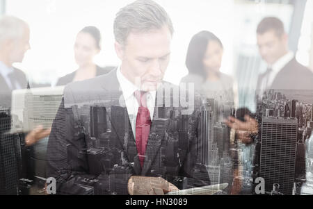 Imprenditore maturo con tavoletta digitale mentre si sta in piedi in ufficio Foto Stock