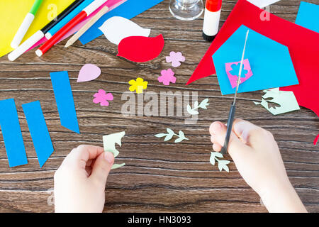 Il bambino tagli fuori i dettagli della carta. Il bambino creare una molla carta per biglietti d'auguri. Fatti a mano. Craft per bambini. Per i bambini il Progetto Arte, ricamo, cra Foto Stock