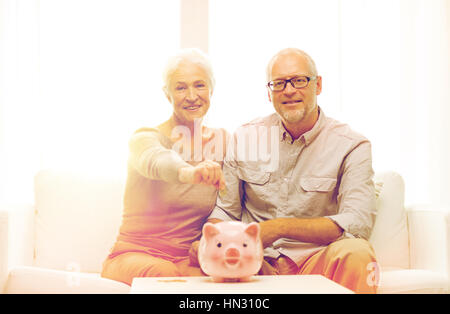 Coppia senior con il denaro e il salvadanaio a casa Foto Stock