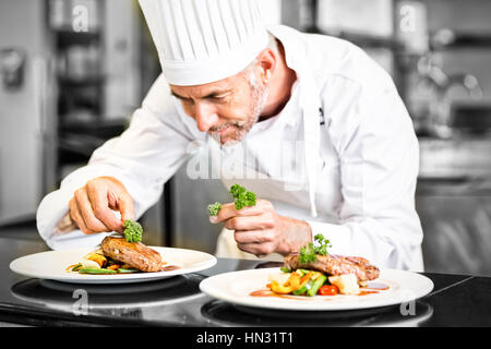 Primo piano di un concentrato maschio guarnitura dello chef in cucina il cibo Foto Stock