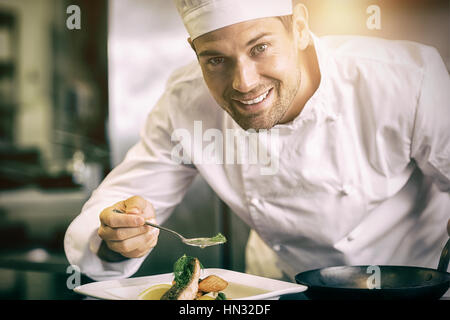 Primo piano di un sorridente maschio guarnitura dello chef in cucina il cibo Foto Stock