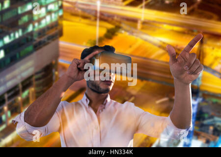 Uomo che utilizza una realtà virtuale dispositivo contro un angolo alto vista della strada incandescente Foto Stock