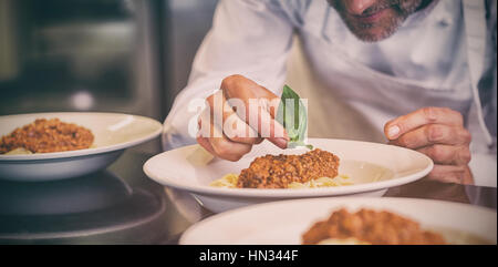 Vista dettagliata sezione intermedia di un maschio di farcitura chef in cucina il cibo Foto Stock