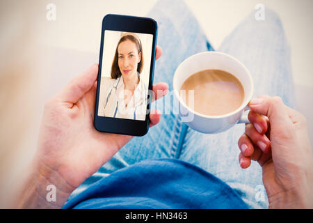 Donna che utilizza il suo telefono mobile e la coppa di ritegno del caffè contro close-up ritratto di donna sorridente Foto Stock