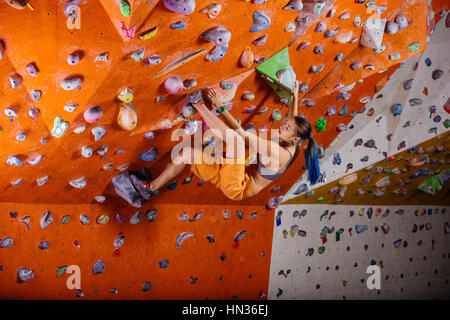 Donna bouldering in palestra di arrampicata Foto Stock