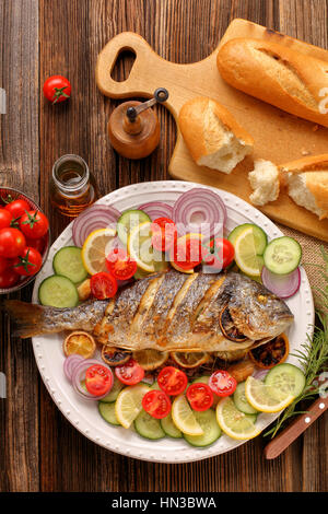 Grigliate di pesce con baguette e verdure sulla piastra Foto Stock