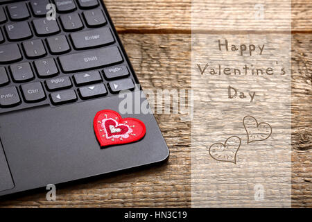 Cuore rosso a sinistra su computer desktop con iscrizione felice il giorno di San Valentino Foto Stock