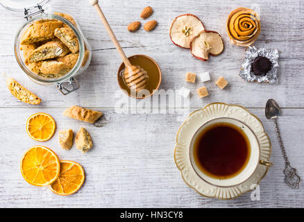 Gustosi e sani biscotti di mandorle, ricco di vitamine e minerali in un vasetto di vetro, una tazza di tè, miele, mandorle, cioccolatini, secche Mele, secche di limoni e su Foto Stock