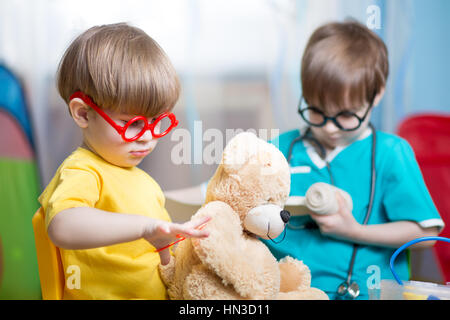 I bambini giocando medico e indurendo il giocattolo di peluche in ambienti interni Foto Stock