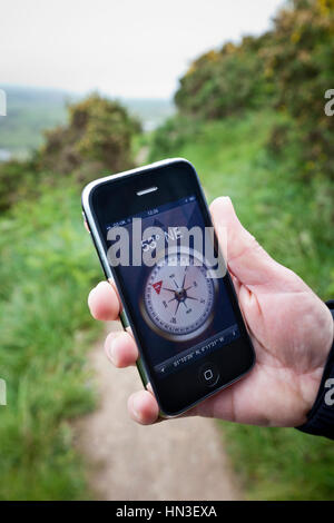 Woolacombe, Regno Unito - 17 Maggio 2011: Close-up di una femmina la mano che regge un Apple iPhone 3GS in esecuzione l'applicazione bussola che mostra la posizione e Foto Stock