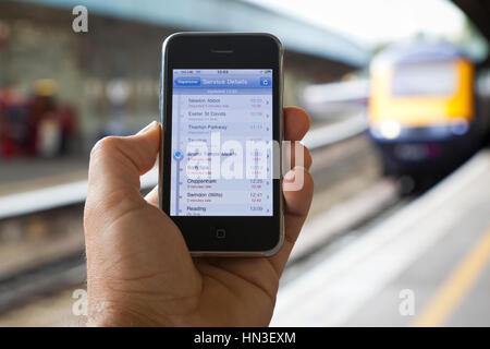 Bristol, Regno Unito - 4 Ottobre 2011: un maschio di mano che tiene un Apple iPhone 3Gs a Bristol Temple Meads Station con l'avvicinamento di un locomotore o Foto Stock