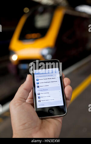 Bristol, Regno Unito - 4 Ottobre 2011: un maschio di mano che tiene un Apple iPhone 3Gs a Bristol Temple Meads Station con un treno al di fuori della messa a fuoco nel Foto Stock