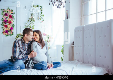 La donna incinta e il marito holding babbucce Foto Stock