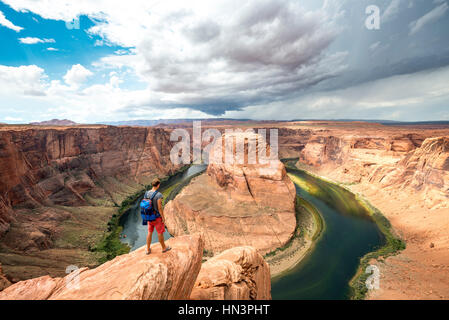 Giovane uomo su una roccia, a Ferro di Cavallo curva, ansa del fiume Colorado, re Bend, Glen Canyon National Recreation Area, Page Arizona Foto Stock