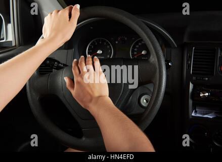 Le mani del driver utilizzando il clacson isolato su nero Foto Stock