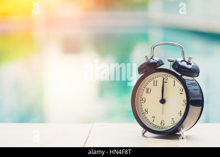 Ore 12 orologio retrò presso la piscina all'aperto tempo di vacanza concetto. Foto Stock