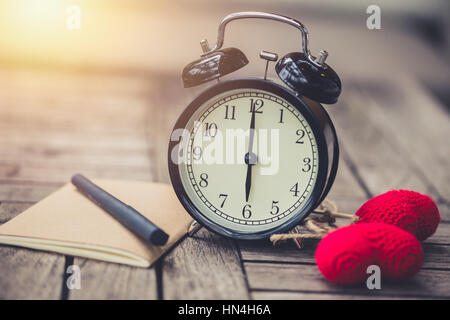 Retrò orologio alle ore 6 con notebook o memo sul tavolo di legno, tempi di amore di scrittura della memoria concetto diario vintage del tono di colore. Foto Stock